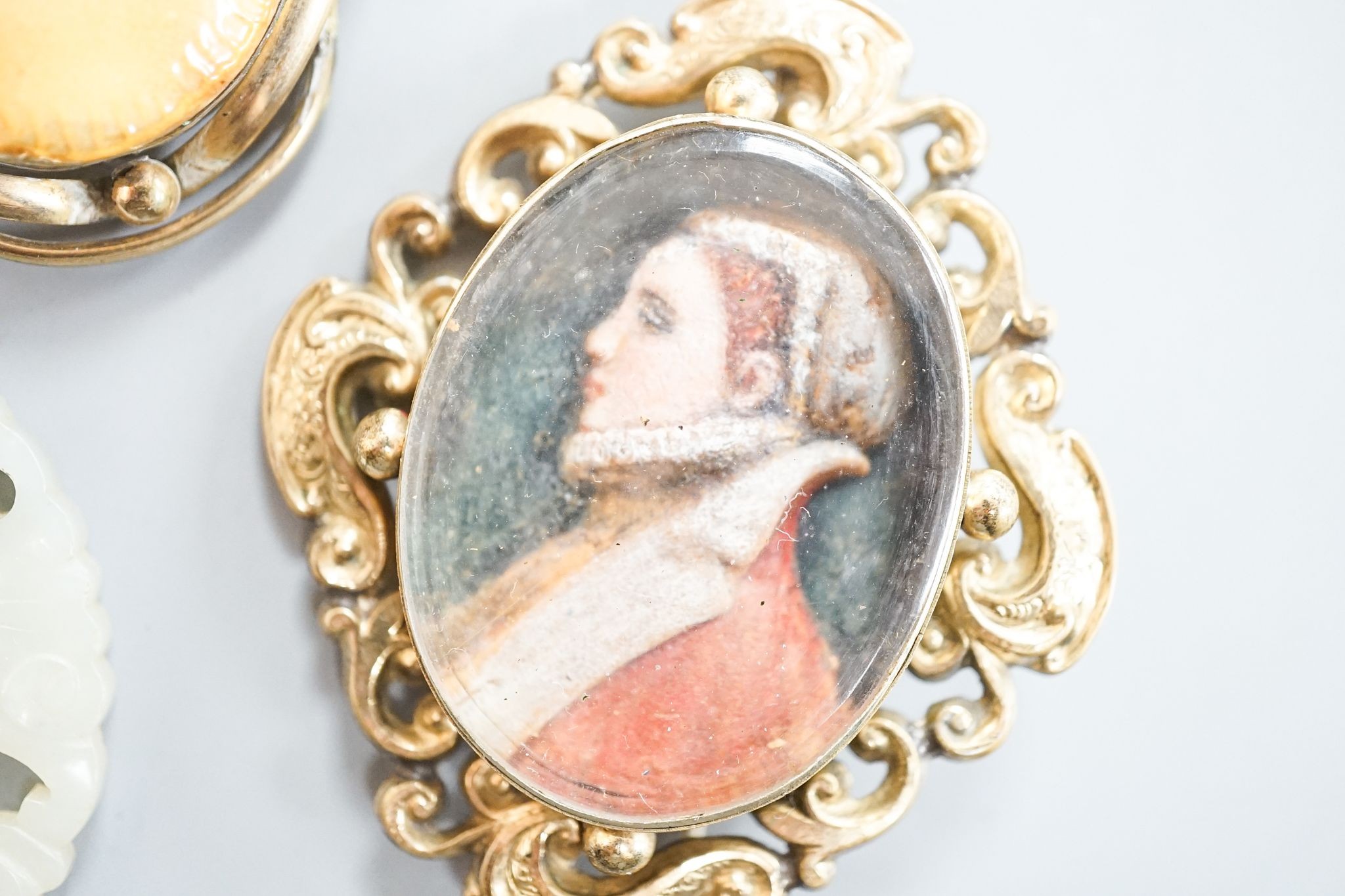 A 19th century gilt metal mounted brooch, with inset oval painted wax bust of a lady to dexter, 60mm and four other items including a 9ct mounted oval tiger's eye quartz pendant.